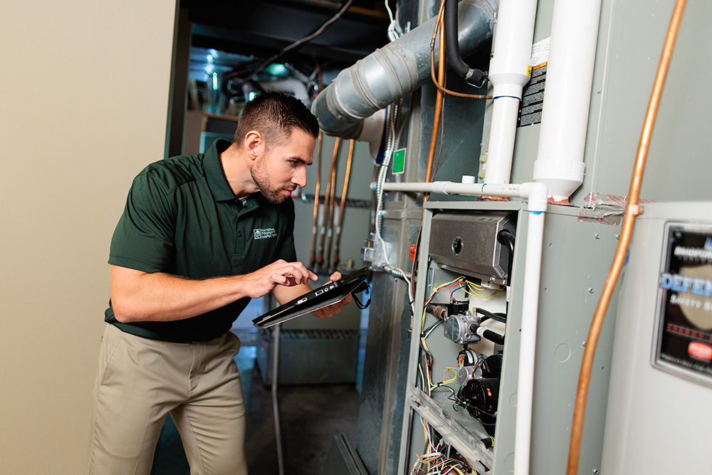 An NPI inspector checks utilities and wiring while holding a tablet.