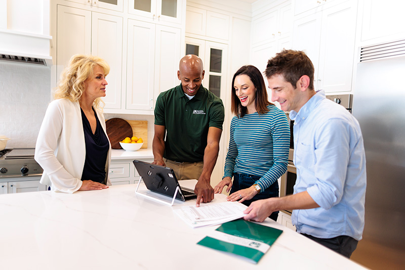 An NPI inspector points to a detail in the inspection report as he speaks with two happy clients.