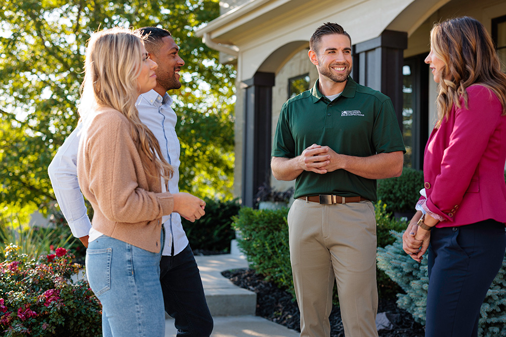 An NPI inspector stands with clients in front of a home.