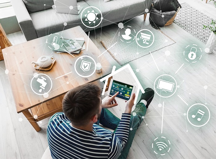 man seated on floor holding a tablet to coordinate his home's utilities